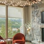 Elegant living room with Lutron motorized shades partially lowered over large windows, showcasing a scenic mountain view.